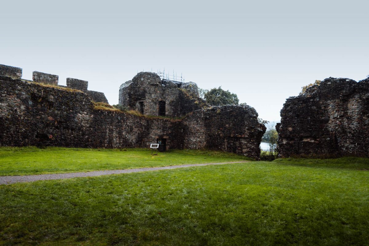 The curtain wall and towers of Old Inverlochy Castle round its grassy courtyard.