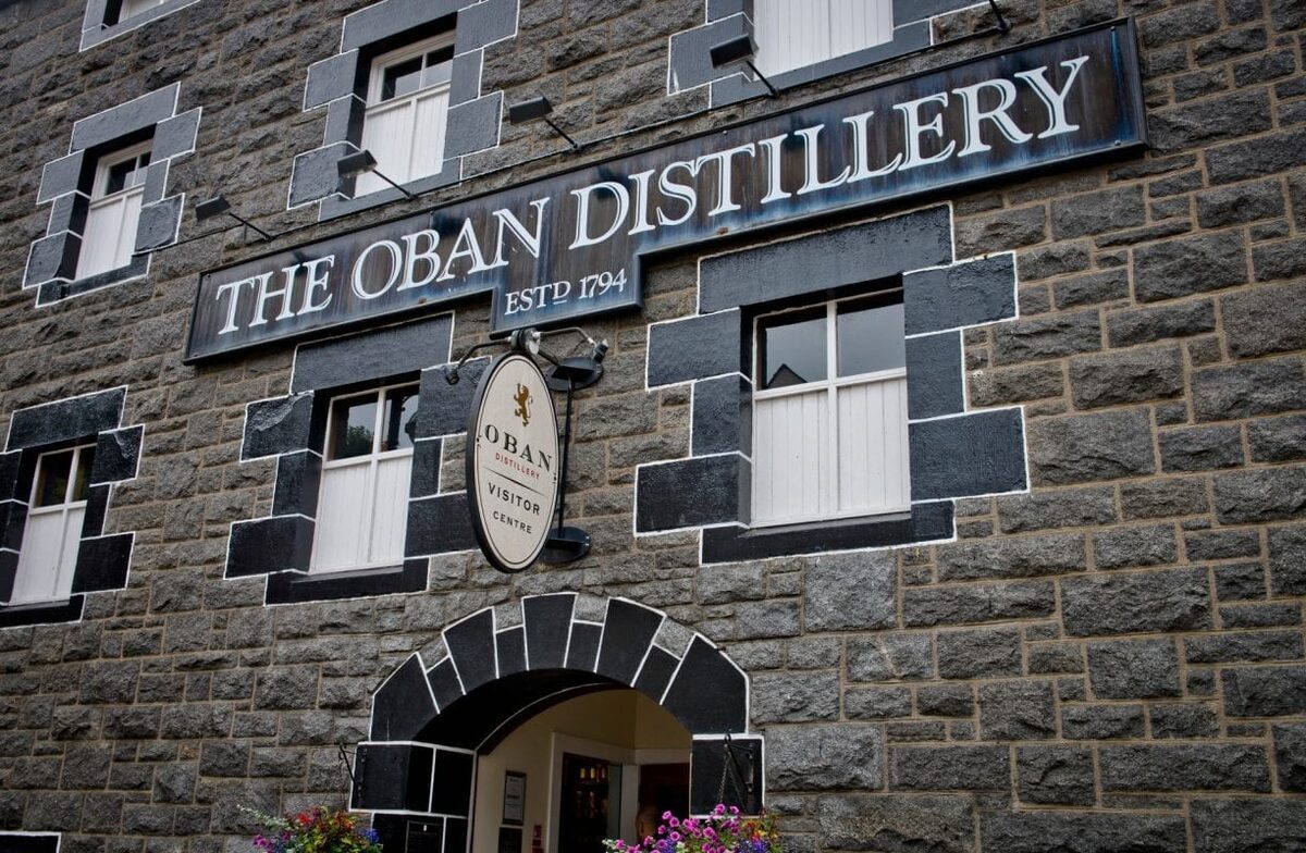 The dark stone front of the Oban Distillery and its sign, Estd 1794.