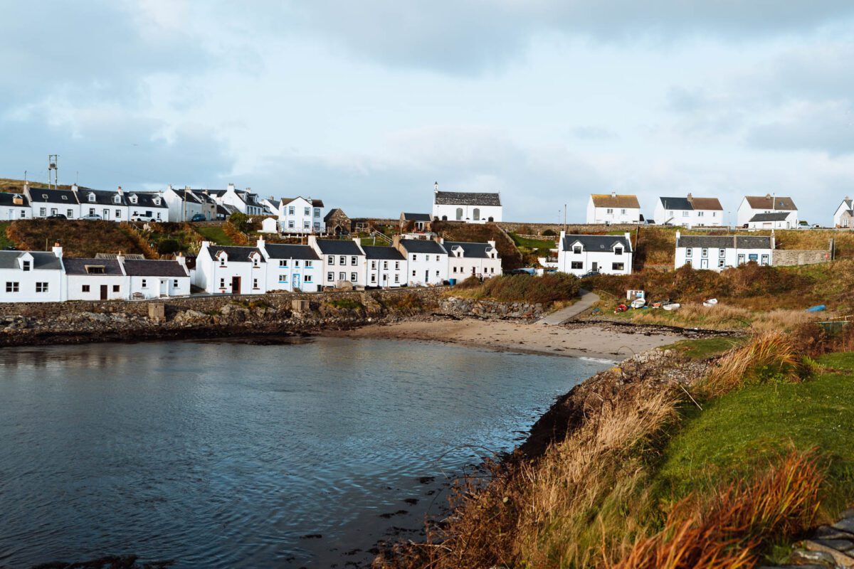 The white cottages of Portnahaven round the head of the inlet, a small sandy beach below.