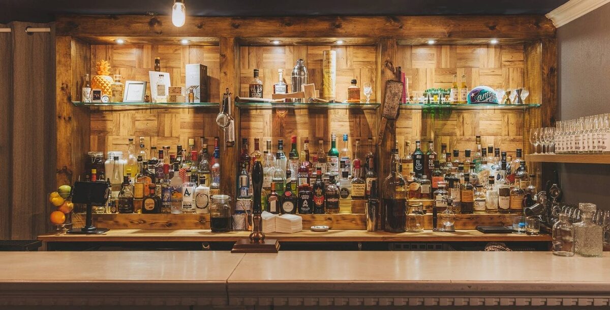 Wooden bar with glass shelves lined with spirits and beer taps