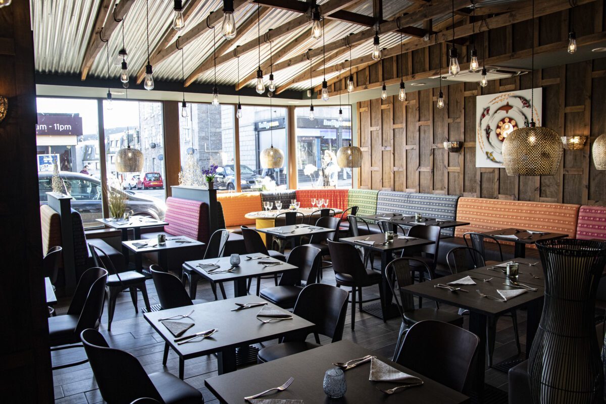 Restaurant interior with coloured booth seating and hanging bulb lights