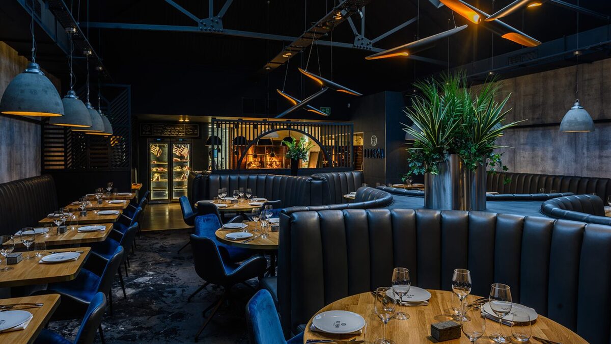 Restaurant interior with leather booths, blue chairs and set wooden tables
