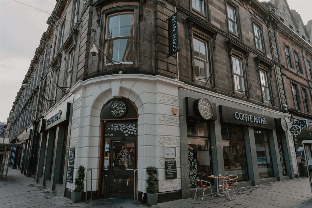 Corner building with curved white facade and Coffee at No6 signage on a city street