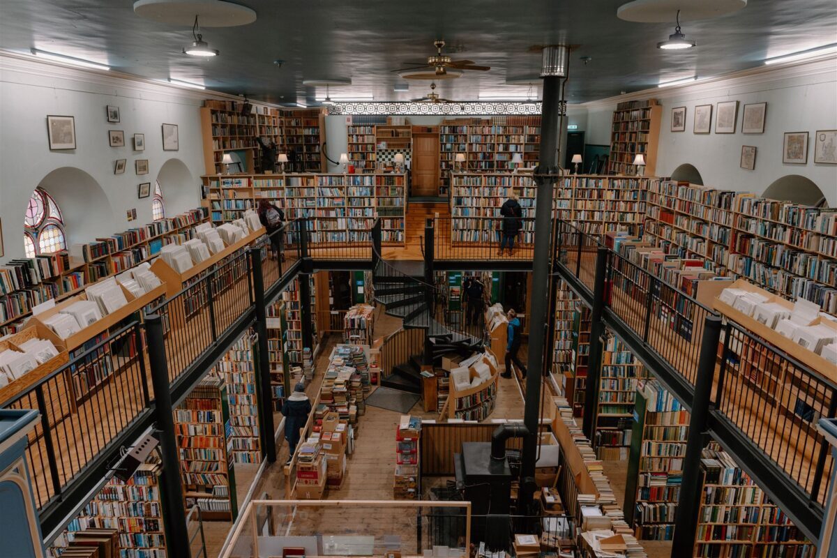 Spiral staircase links galleried floors of packed bookshelves in a domed bookshop