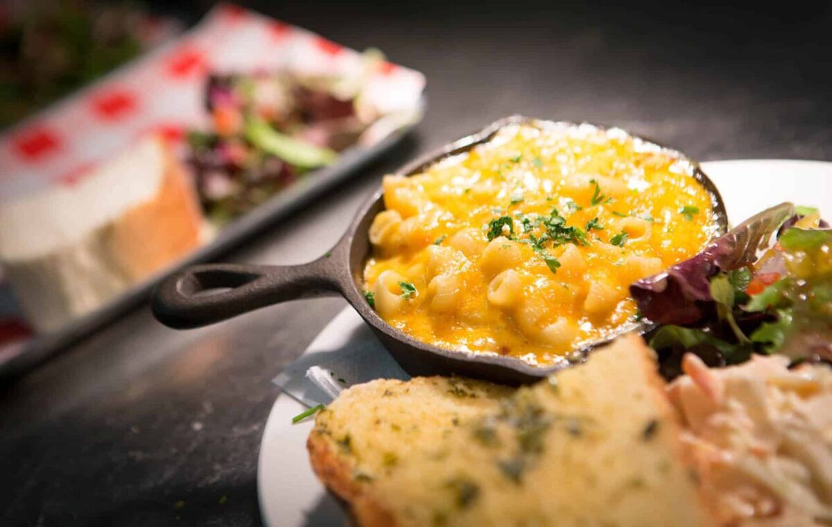 Macaroni cheese served in a mini skillet with garlic bread and salad