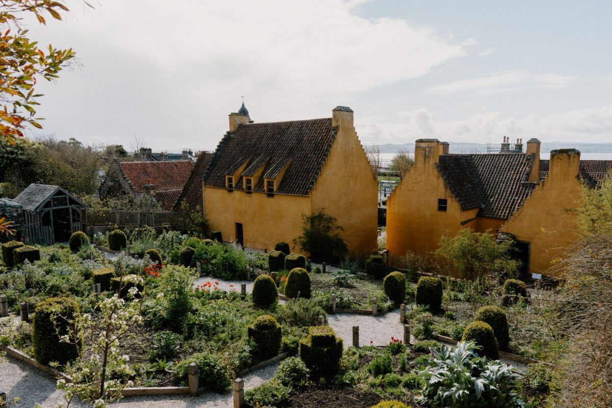 Ochre gabled houses overlook a walled garden with clipped topiary and gravel paths