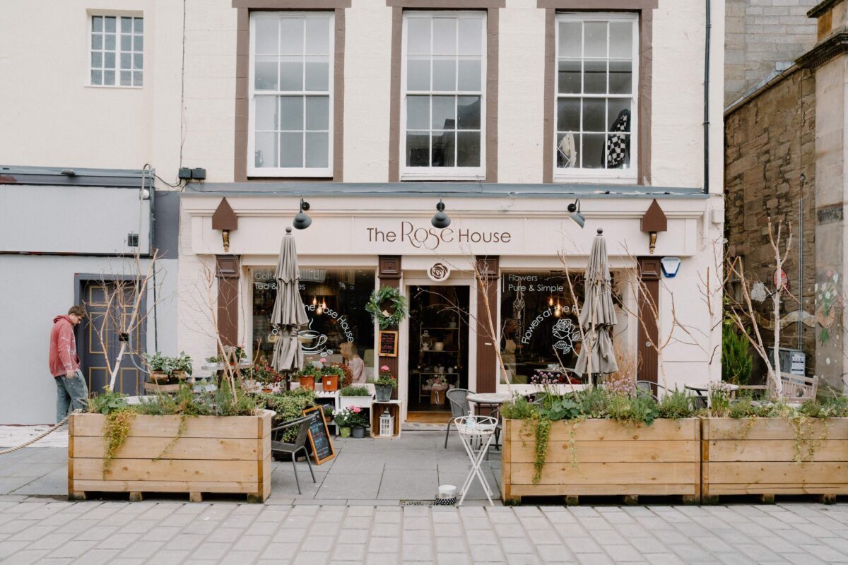 Wooden planters flank The Rose House shopfront on a quiet street