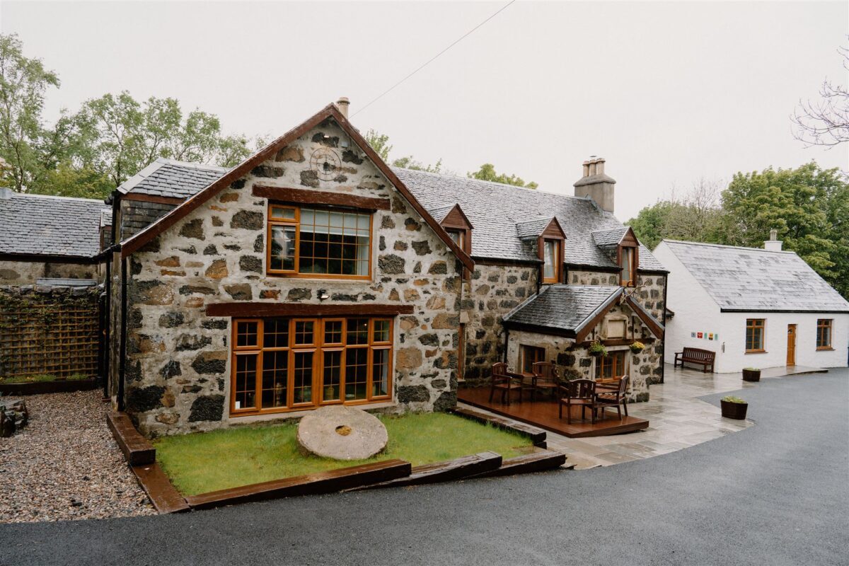Stone cottage with millstone in garden, wooden decking and outdoor seating