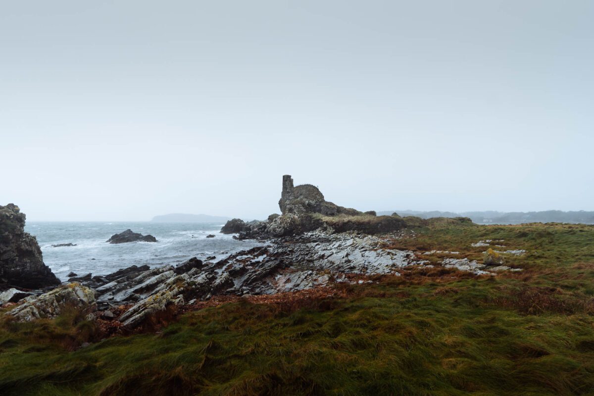 The broken tower of Dunyvaig Castle on its rocky point, the sea grey beyond.