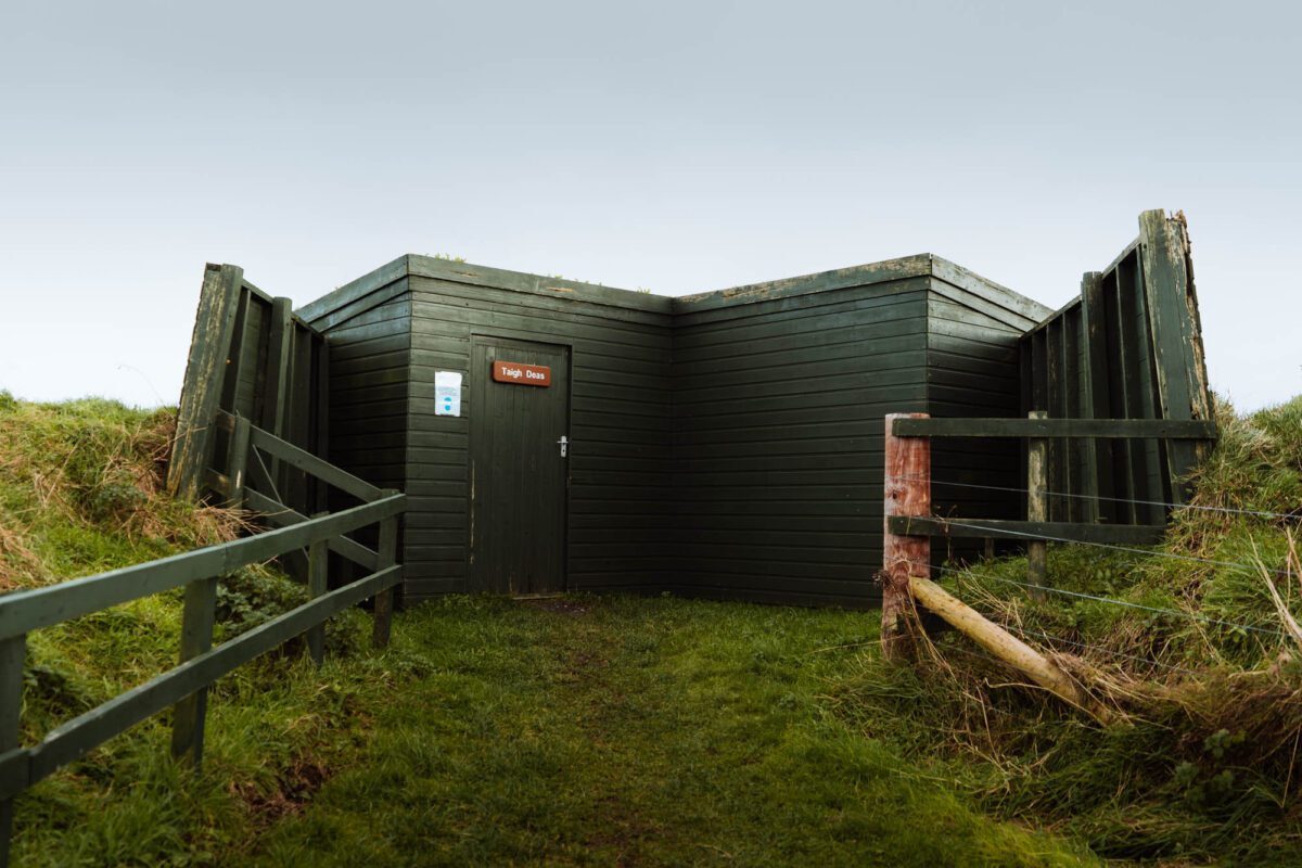 The dark green hide at Loch Gruinart, set low in the grass.