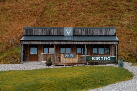 Wooden bistro building with a stag emblem, set against a hillside