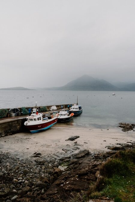 Fishing boats moored at a stone pier beneath misty hills
