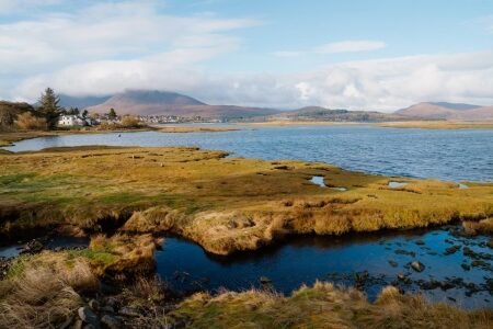 Rough grass and pools on the shore at Broadford, the bay and hills beyond.