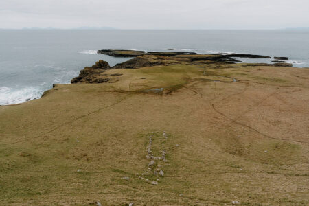 Grassy headland with a stony path leading towards rocky sea cliffs