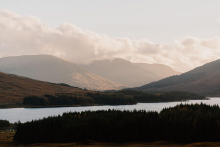 Loch Tulla among pinewoods and moorland in evening light, peaks beyond.