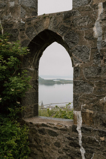 Arched stone window frames a harbour and islands beyond