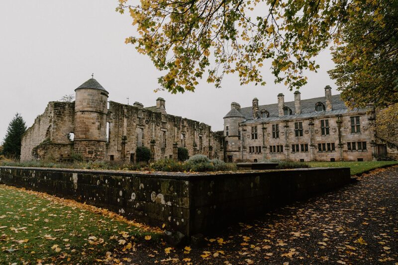 Ruined abbey walls beside Balcarres House, autumn leaves scattered across the path