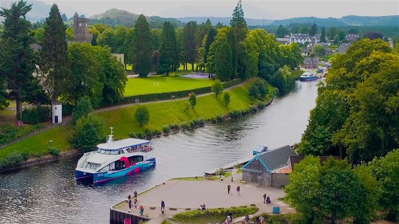 Aerial view of Fort William's river with a tour boat moored beside a park