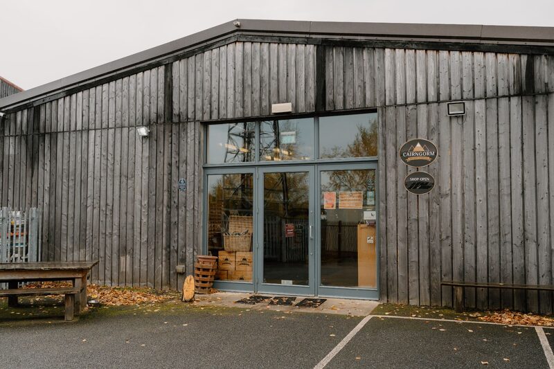 Timber-clad building entrance with glass doors and round wooden sign